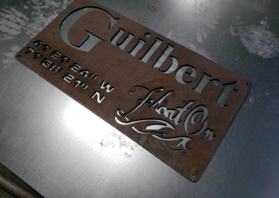 Rusted metal sign with the customers last name, and latitude and longitude of his home town