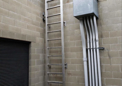 Aluminum ladder bolted to a block wall