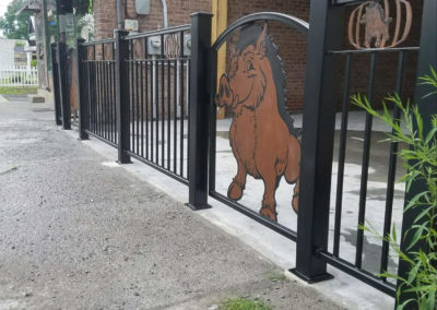 Black steel fencing with a large pig centered in a gate